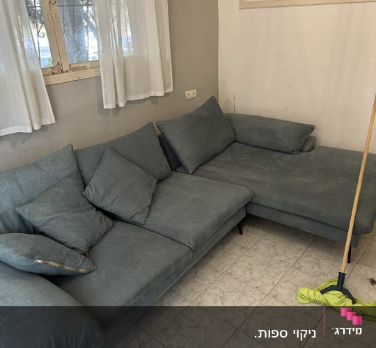 ספה אפורה עם כריות ומגב על הרצפה